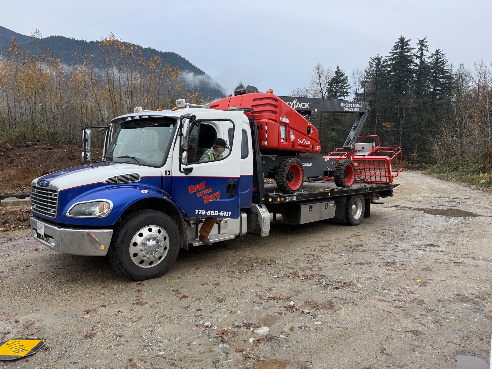 Tow Of The Day flatbed hauling heavy machinery in the mountains